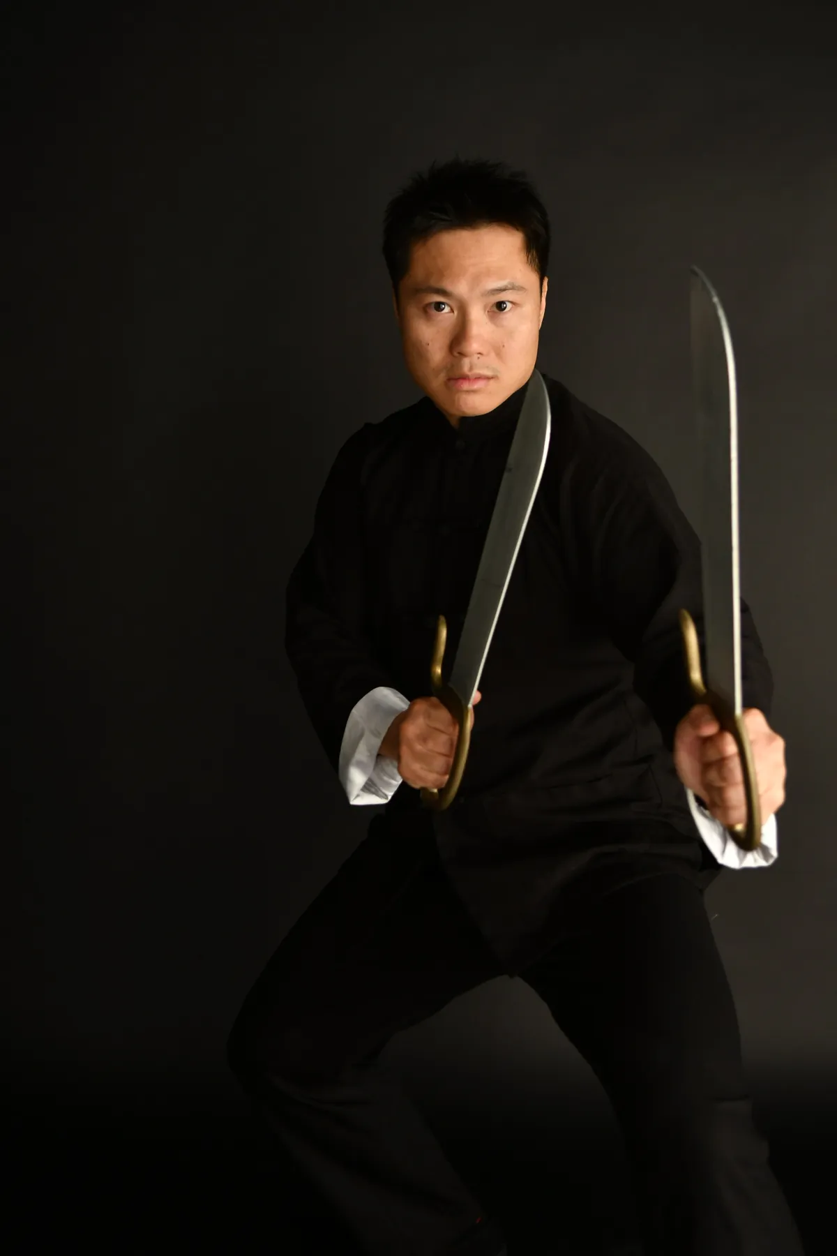 Master Leo Au-Yeung holding two butterfly swords in a low Wing Chun stance