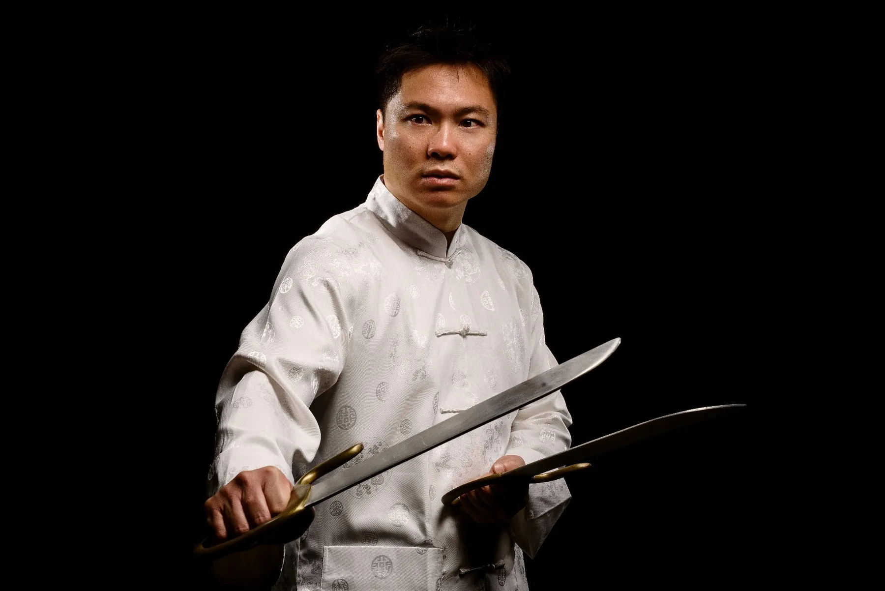 Master Leo Au-Yeung in white silk holding butterfly swords